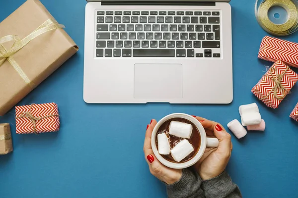 Mãos de mulher com cacau quente com marshmallows e laptop, presentes , — Fotografia de Stock