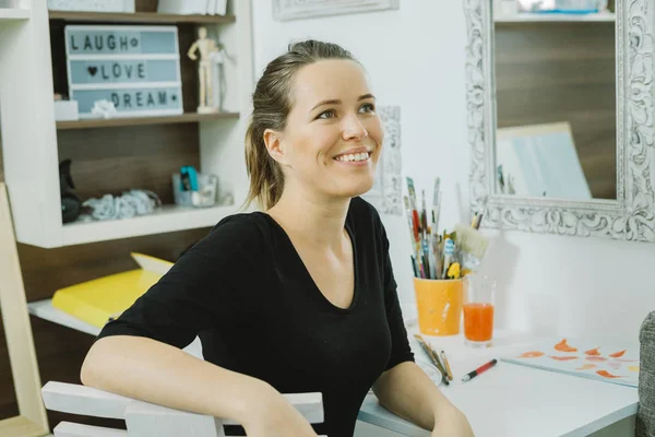 Portrait of smiling woman artist with paintbrush at the workplac — Stock Photo, Image