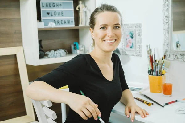 Mulher sorridente artista com pincel no local de trabalho — Fotografia de Stock