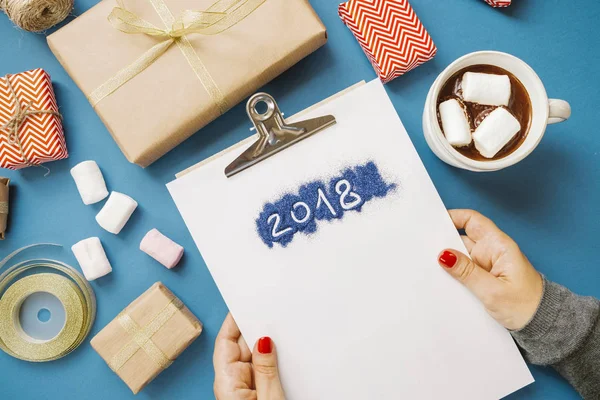 Women's hands with paper with the word 2018, hot cocoa with mars — Stock Photo, Image