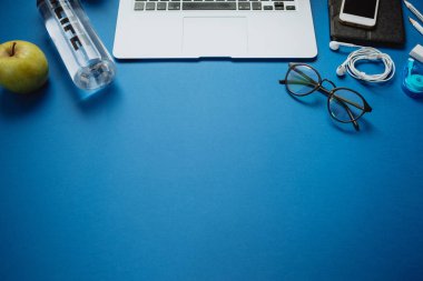 Dizüstü bilgisayar, kalemler, su, elma ile sağlıklı insan için çalışma alanı,