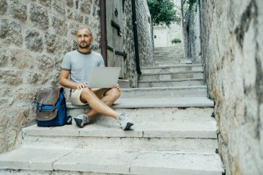 Serbest meslek sahibi adam ve sokağın ortasında bir dizüstü bilgisayar üzerinde çalışan bir gezgin,