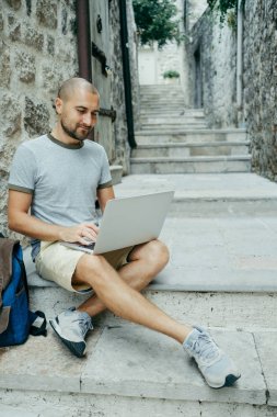 Serbest meslek sahibi adam ve sokağın ortasında bir dizüstü bilgisayar üzerinde çalışan bir gezgin