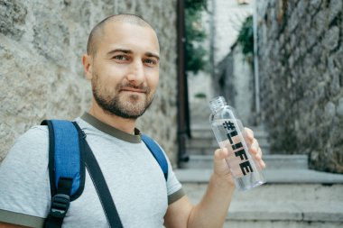 Gülümseyen adam sokakta, Euro plastik şişe suyu içer