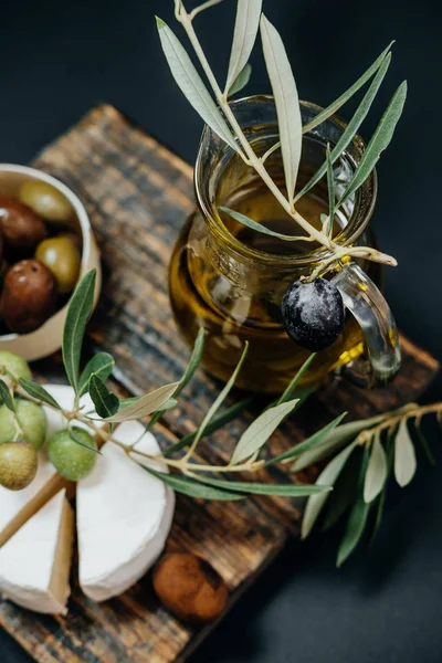 Sağlıklı snack: koyu ve yeşil zeytin, yağ, bir tahta üzerinde keçi peyniri — Stok fotoğraf