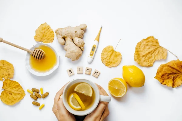 Manos de mujer con té, Palabra de madera enferma, limón, termómetro, ging — Foto de Stock