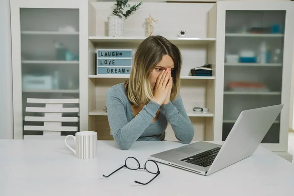 Stanco giovane donna occhiali di lavoro sul computer portatile mentre seduto in — Foto Stock