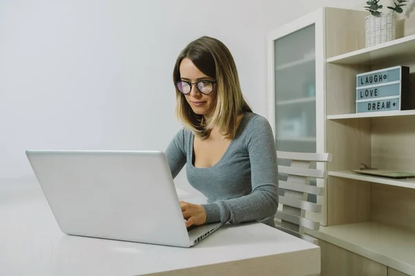 Sebevědomá mladá žena brýlatý, pracují na notebooku při sezení — Stock fotografie