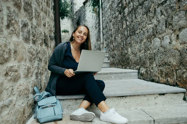 Молодая женщина фрилансер в темно-синем кардигане работает на ноутбуке — стоковое фото