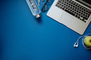 Dizüstü bilgisayar, kalemler, su, elma ile sağlıklı insan için çalışma alanı,