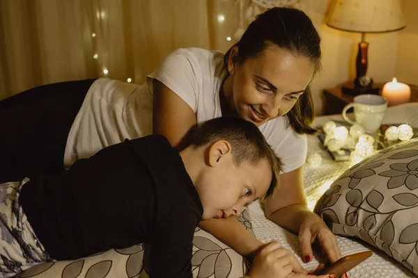 Mother and boy reading on the phone in bed before going to sleep — Stock Photo, Image