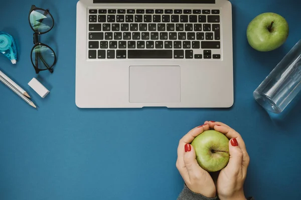 Frauenhand auf Laptop mit Bleistiften, Wasser, Apfel, Telefon, Brille, — Stockfoto