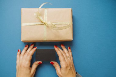 Kredi kartı ve hediye üzerinde mavi arka plan ile kadının el