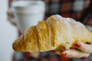 Fincan çay ve kruvasan tutan eller