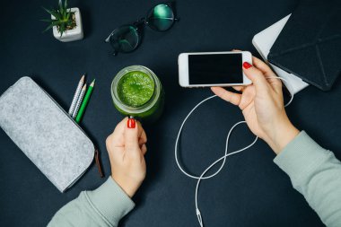 Taze yeşil smoothies ile telefon ve kavanoz ile eller