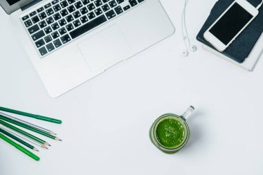 Yeşil smoothie ve beyaz backg laptop ile sağlıklı bir çalışma alanı