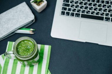 Sağlıklı kavramı. Masaüstü yeşil smoothie ve siyah laptop ile