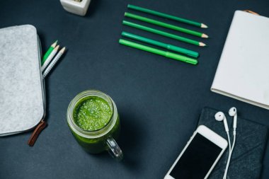 Telefonu, kulaklık defter ve yeşil s ile yaratıcı çalışma alanı