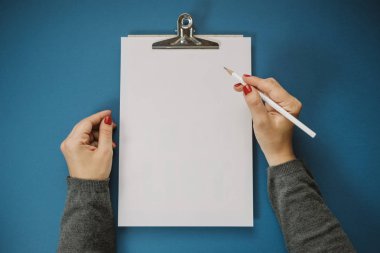 Mavi bir arka plan üzerinde beyaz bir sayfa tutan eller