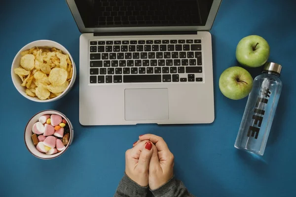 Work space with laptop, candy, chips, water and apple on blue ba — Stock Photo, Image