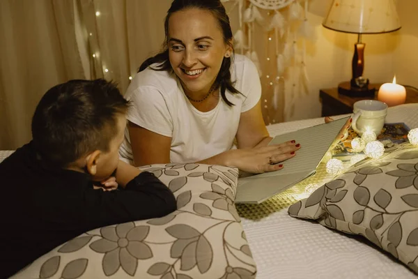 Smiling Mother and boy reading a book in bed before going to sle — Stock Photo, Image