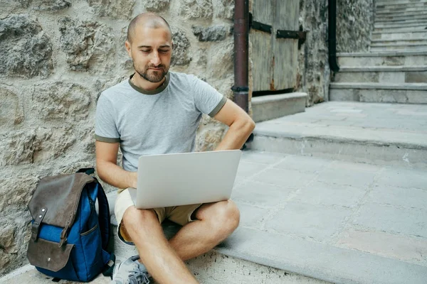 Serbest meslek sahibi adam ve sokağın ortasında bir dizüstü bilgisayar üzerinde çalışan bir gezgin