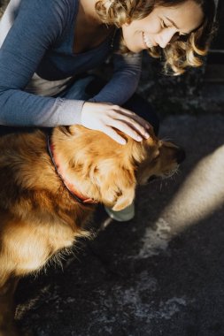 Bir köpek okşayarak ve gülümseyen genç güzel kadın