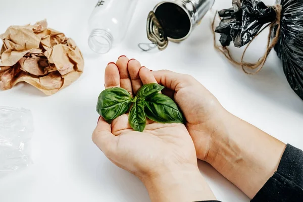 Concepto de gestión de residuos. Manos de mujer con hoja verde y bolsa de basura —  Fotos de Stock