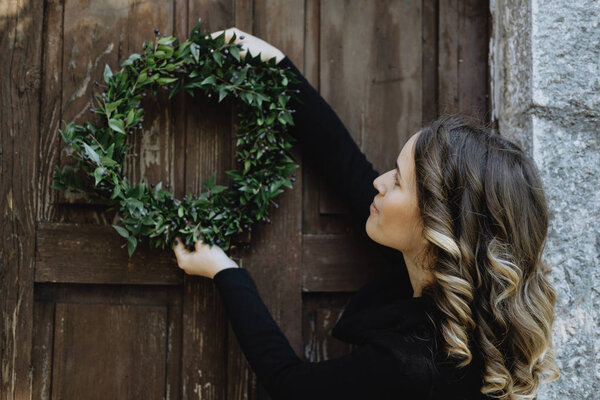 Young woman hanging a Christmas wreath on her home Stock Photo
