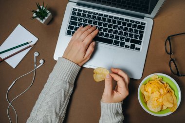 Cips ve kahverengi zemin üstünde laptop ile kadın el. Üstten Görünüm.