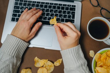 Cips ve kahverengi zemin üstünde laptop ile kadın el. Üstten Görünüm.