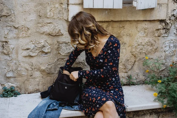 Hermosa chica buscando algo en una bolsa al aire libre — Foto de Stock