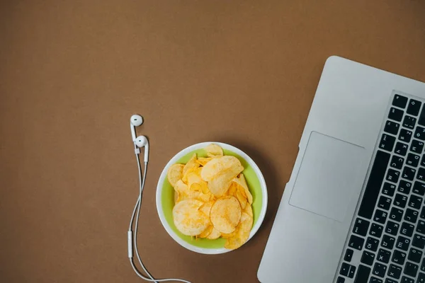 Desktop with laptop and headphones and chips. Unhealthy concept. — Stock Photo, Image