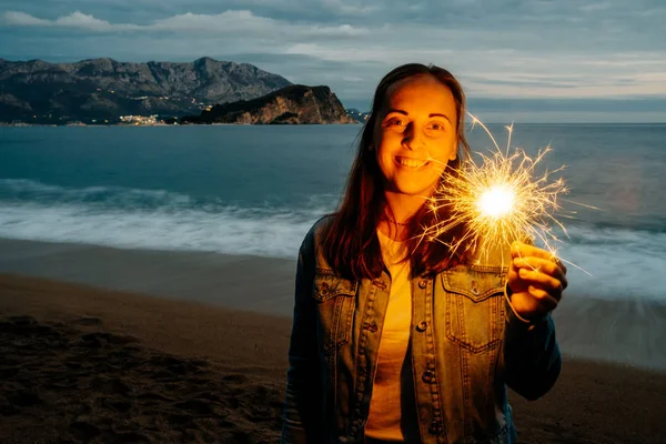 Foto al aire libre de la joven feliz mujer sonriente sosteniendo sparklernear — Foto de Stock