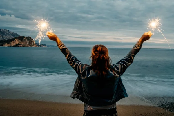 Visão traseira da jovem mulher sorridente feliz segurando sparklernear o — Fotografia de Stock