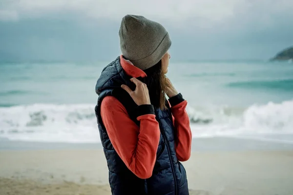 Mladá žena nosí sportovní vesta stojí u moře — Stock fotografie