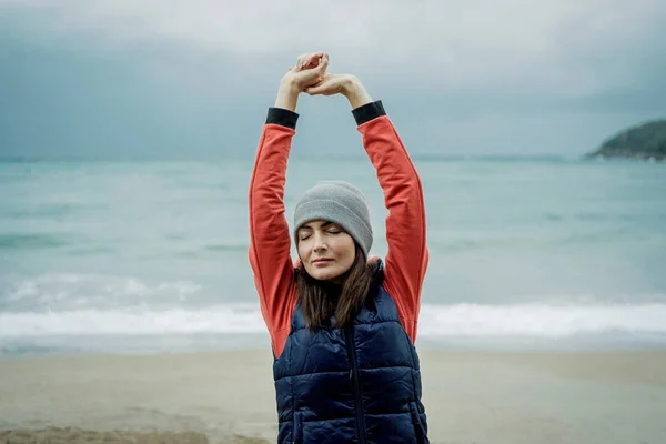 Radostné mladá žena stojící na chladné zimní beach a úsek — Stock fotografie