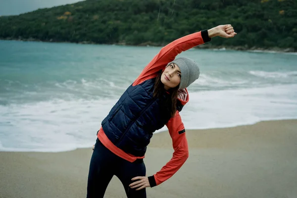 Jovem vestindo um colete esportivo exercitando-se no mar de inverno — Fotografia de Stock