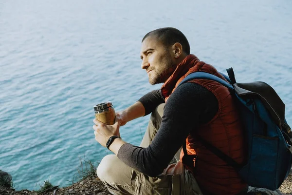 Voyageur homme portant un gilet de sport assis sur une montagne avec un bac — Photo