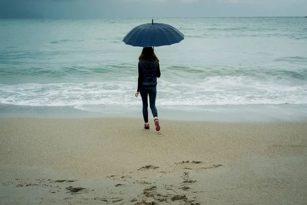 Jeune femme marchant avec un parapluie devant la mer en hiver ou une — Photo