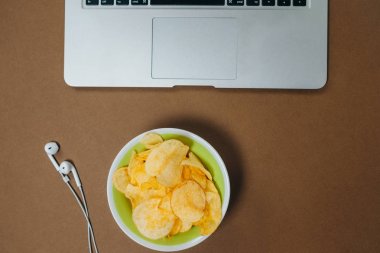 Cips ve kahverengi zemin üstünde laptop. Üstten Görünüm. Düz yatıyordu
