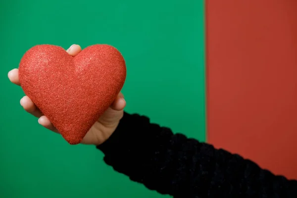 Coração vermelho em mãos de mulher em fundo vermelho e verde. Valentim — Fotografia de Stock