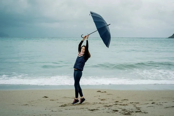 Jeune femme debout avec un parapluie devant la mer en hiver ou — Photo