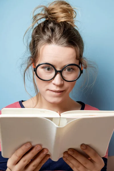 Jonge vrouw leest een boek op een blauwe achtergrond — Stockfoto