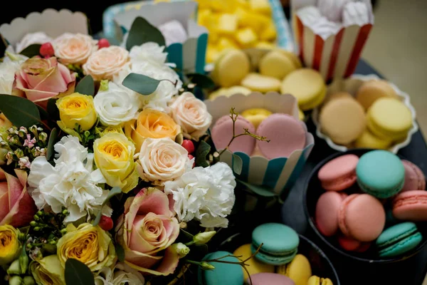 Sweet table at the feast. Flowers and multi-colored macaroons — Stock Photo, Image