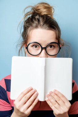Genç güzel kadın mavi bir arka plan üzerine bir kitap okur