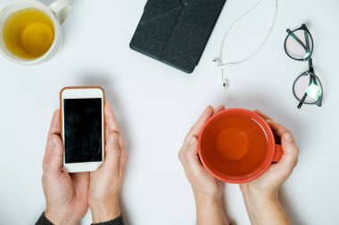 Pnone beyaz tablo, üstten görünüm ile çay bardak iki el ele tutuşur