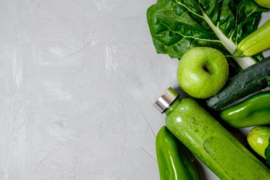 Yeşil sebze ve bir plastik şişe üzerinde gri bir bac smoothies