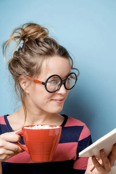 Mooie jonge vrouw met rode mok tegen blauwe achtergrond. Studio — Stockfoto