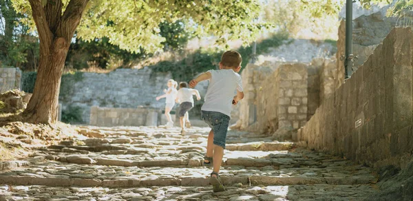 Lopen de kinderen door het park van de zomer, het uitzicht vanaf de achterkant. — Stockfoto